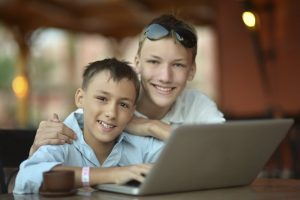 boys sitting with laptop and coffee in hotel