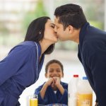 little boy is laughing when seeing his parents kissing before breakfast