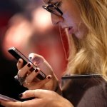 woman-compares-two-smartphones-an-iphone-and-a-samsung-galaxy-at-a-trade-show