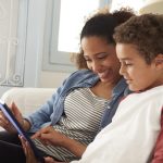 Mother And Son Sitting On Sofa Using Digital Tablet